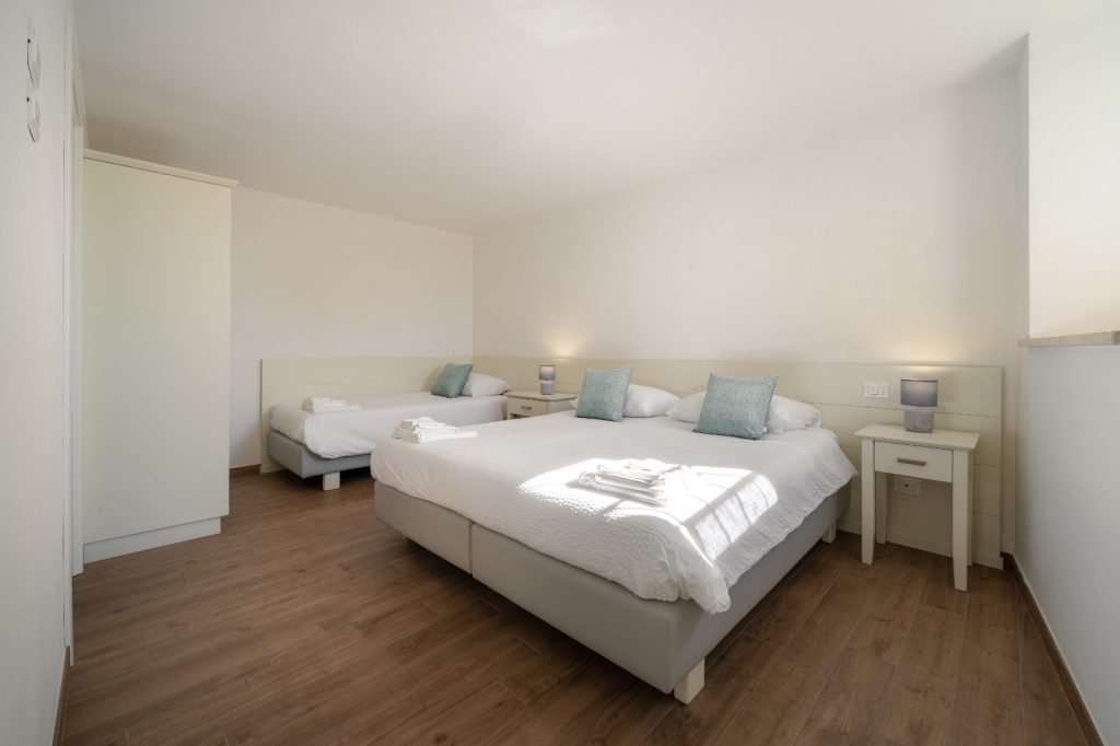 Immagine del letto matrimoniale dell'Appartamento 1 degli Appartamenti alla lanterna con delle coperte bianche e illuminato dalla finestra a destra